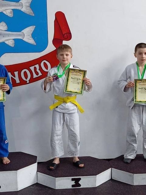 Мальчик с жёлтым поясом и грамотой на пьедестале