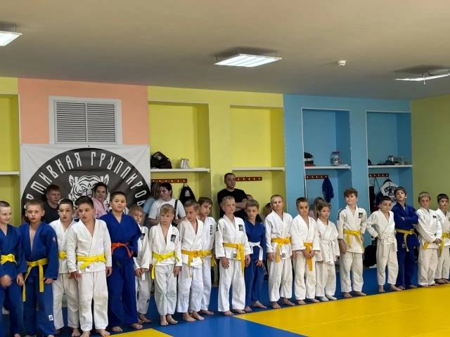 Дети в кимоно с жёлтыми поясами стоят в строю в зале